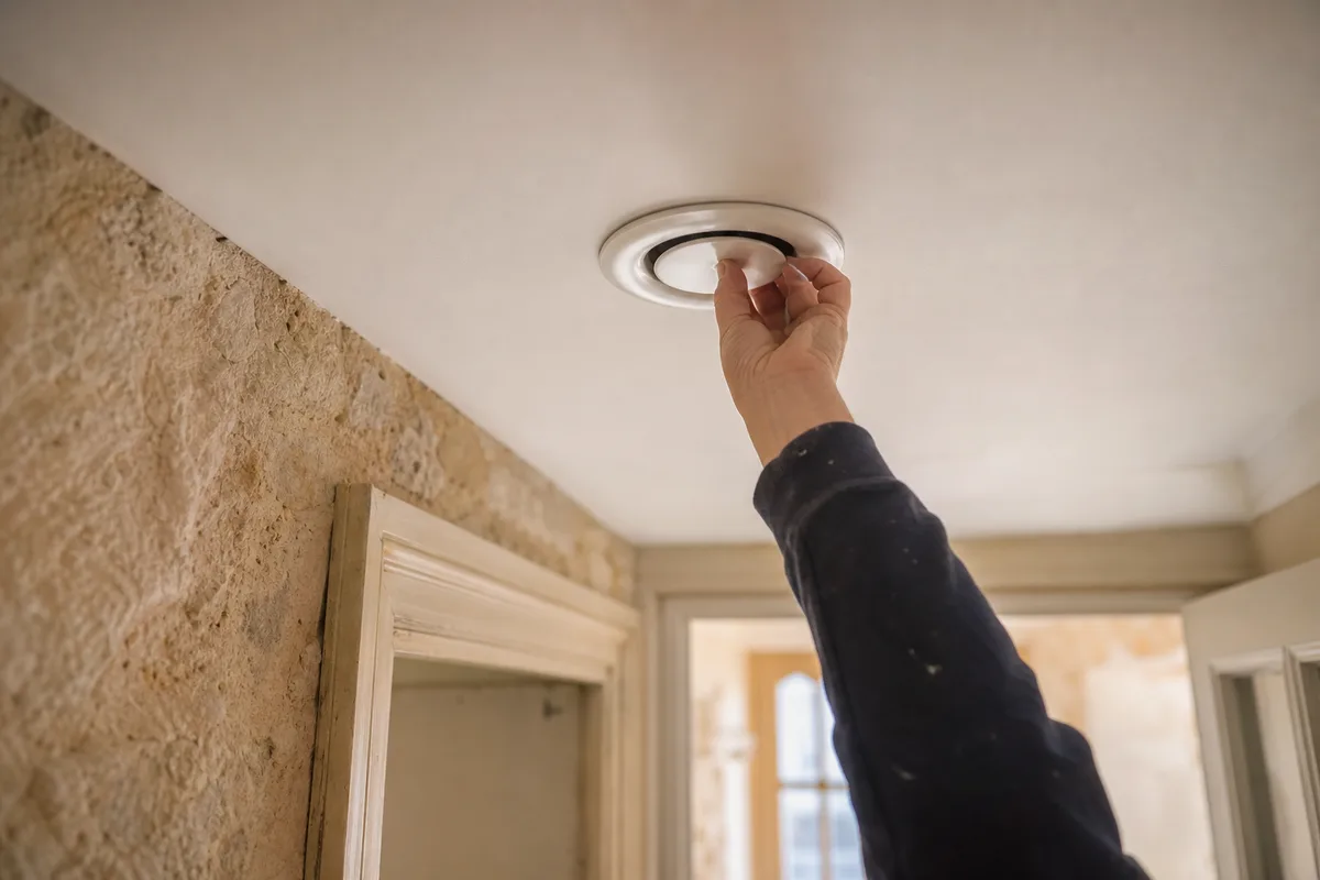 Bouche de soufflage encastrée au plafond d’un couloir dans une maison en pierre calcaire